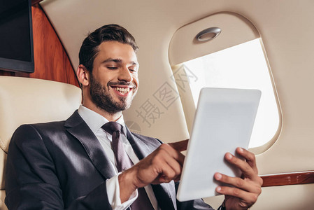 在私人飞机上使用数字平板电脑的身着西装面图片