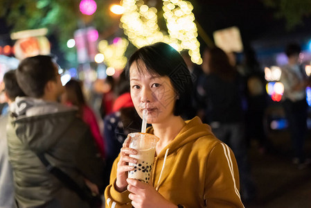 亚裔女在夜市上喝着著名的图片