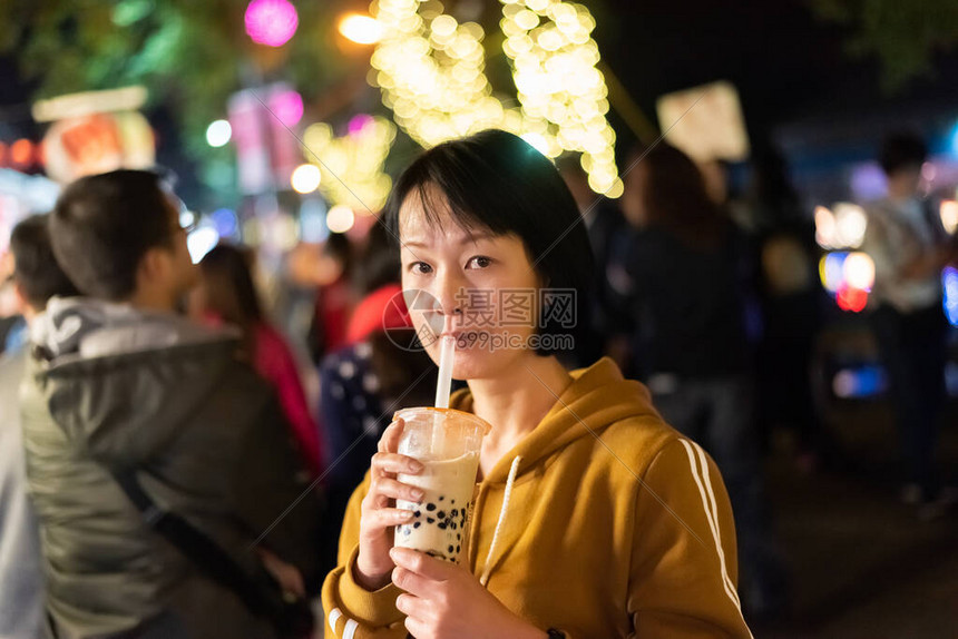 亚裔女在夜市上喝着著名的图片