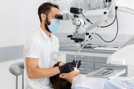 专业大胡子男牙医在牙科治疗中使用现代技术图片