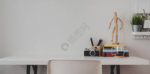 配备办公室用品和白色木桌背景和白墙上装饰品的最小图片