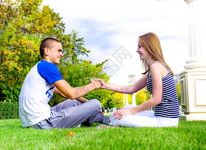 年轻恩爱的夫妻坐在草地上享受假期图片