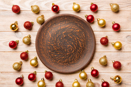 木制背景上带有红色和金色小玩意的节日盘子的顶部视图圣诞装饰品和玩具新图片