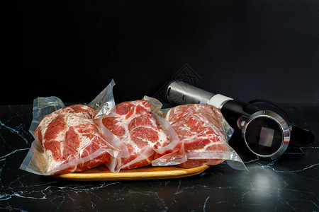 真空低温烹调锅浸入式循环器和深色背景上的肉图片