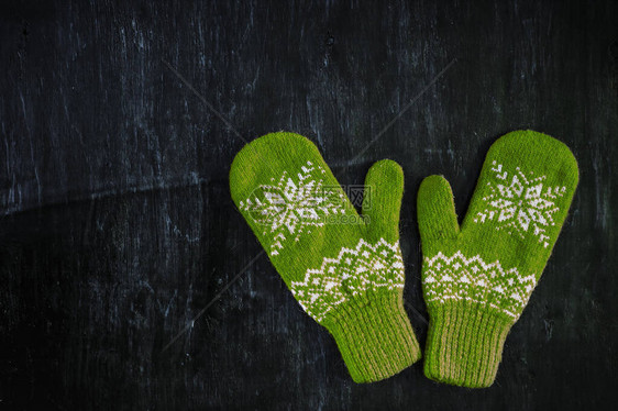 一对蓝绿色编织的手套印在深蓝色绿褐木质古董背景图片