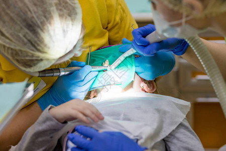 牙医在儿科牙诊所为青春期前的女孩进行牙科填充程序医生使用高速图片