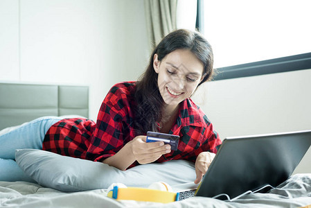 美丽的女人用信卡在笔记本电脑上买东西图片