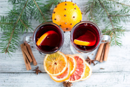圣诞节热辣味葡萄酒含肉桂橙和有树的白木图片