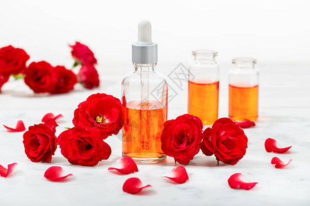 玻璃瓶和有花瓣的小红玫瑰中的紫玫瑰水按摩芳香疗法和有图片