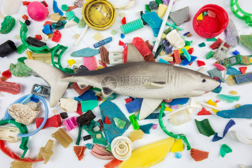 在沙滩上收集的微塑料上的玩具鲨鱼塑料图片
