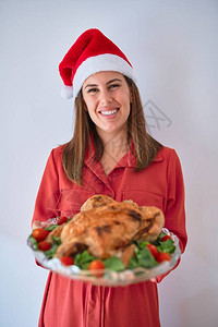 年轻美丽的美女笑着骄傲地拿着感恩节火鸡在餐盘上背景图片