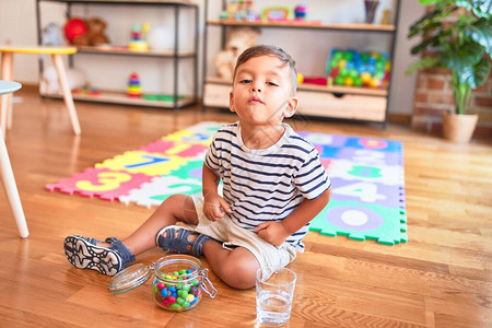 在幼儿园吃小彩色巧克力球坐在拼字游戏上的可爱图片