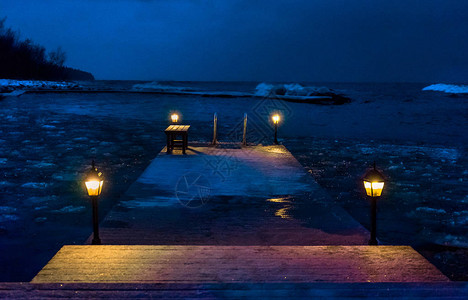 晚上在湖的冬天海湾的一个木码头的灯图片