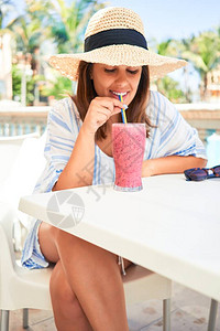 坐在酒店度假胜地酒吧泳池的漂亮女人喝着健康的图片