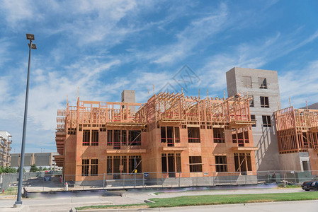 新开发的混合社区与正在建设中的木制公寓已完工的公寓大楼和商业建筑德克萨斯州达拉斯市街道蓝云天空附近的图片