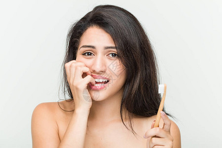 年轻的西班牙女人拿着牙刷咬指甲神经紧张而且图片