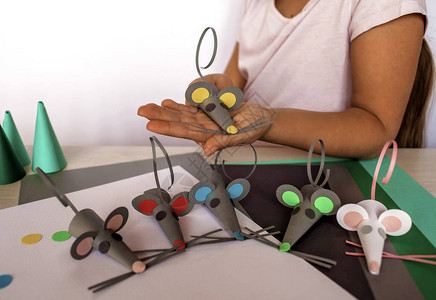可爱的78岁小女孩用彩色纸和装饰打孔器制作手工老鼠图片