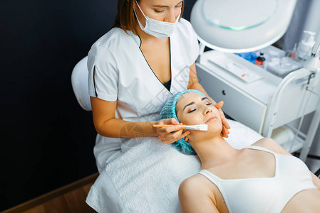 化妆师用刷子清洁女患者的面部皮肤图片