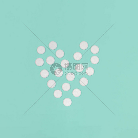 与药片的医学背景世界心脏日的概念医学背景白色药丸以蓝色背景上的心形平躺图片