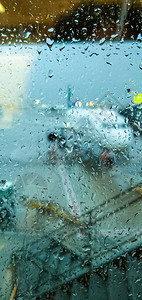 飞行前飞机背景模糊的机场窗户玻璃上的雨滴雨中繁忙的机场飞行前向后推飞图片