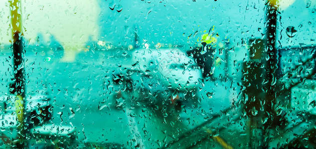 飞行前飞机背景模糊的机场窗户玻璃上的雨滴雨中繁忙的机场飞行前向后推飞图片