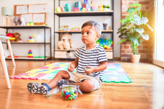 在幼儿园吃小彩色巧克力球坐在拼字游戏上的可爱图片