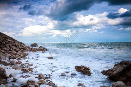 岩石海滨强烈的海浪和风暴海洋以多云的天空为背景图片