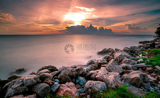 日落时在石滩上的岩石平静的海面美丽的风景黄昏的热带海戏剧夕阳天空和云彩自然之美宁静祥和的概念干图片