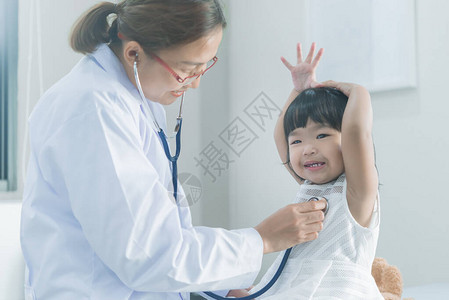 亚洲医生用听诊器检查一个可爱女孩的呼吸和心脏图片