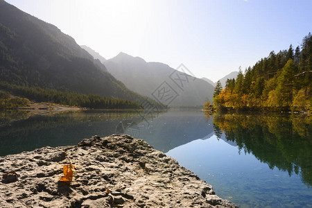 湖边平原上彩色的落地景观树前面有岩图片