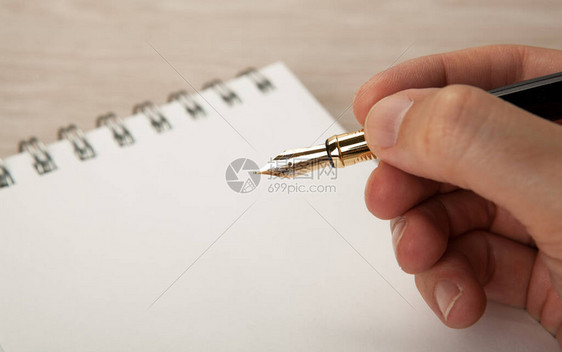 手中的金色钢笔和日记特写图片