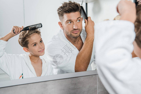 在浴室梳理头发的英俊男人和可爱孩子有图片