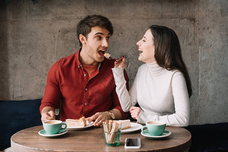 快乐的女朋友喂男朋友在咖啡店图片
