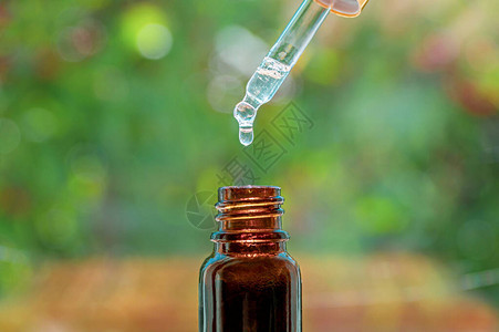 水疗美容概念草本精油按摩油滴入瓶中带精华液滴和瓶子的移液器图片