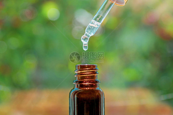 水疗美容概念草本精油按摩油滴入瓶中带精华液滴和瓶子的移液器图片