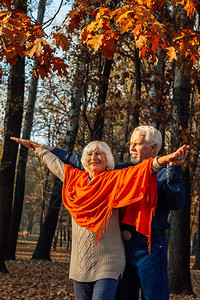 一个快乐的老女人和男人在秋天树叶公园里图片