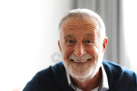 看照相机的愉快的微笑的老人画象图片