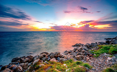 日落时在石滩上的岩石平静的海面美丽的风景黄昏的热带海戏剧多彩日落天空和云彩自然之美宁静祥和的概念干图片