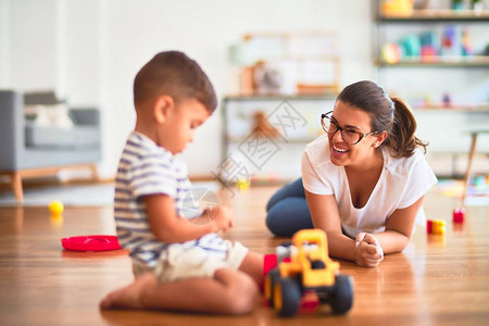 在幼儿园玩拖拉机和汽车的美丽教师和幼儿男图片