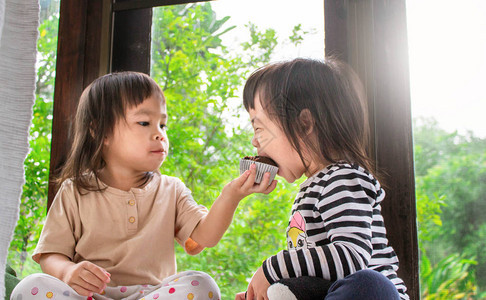 亚洲小女孩和妹正在房间里吃香蕉蛋糕美味极了笑声图片