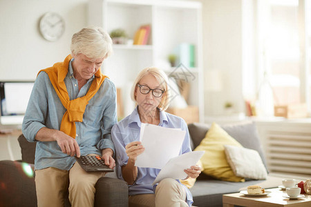 现代老年夫妇在家准备税务报告时计算财务和预算的画图片