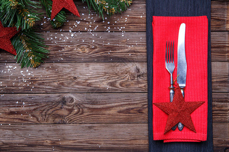 用叉子和刀子装饰的红星和红色餐巾纸和带玩具的圣诞松树枝的圣诞餐桌具图片