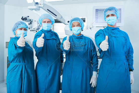 外科医生小组用洗涤剂和面部具在精巧手图片
