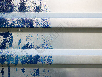 蓝色油漆的金属栅栏特写罗纹灰色铭文的地方项目的背景波纹金属栅栏表面涂成白色和蓝色画污图片
