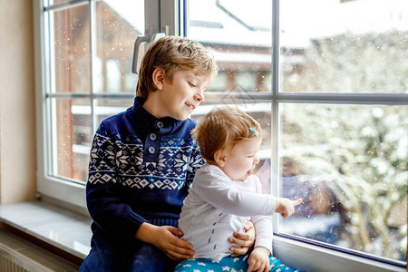 快乐可爱的男孩和可爱的女婴坐在窗边图片