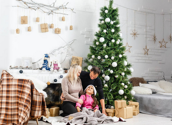 圣诞节家庭年轻父母和女儿在家的Xmas树附近共度时间图片
