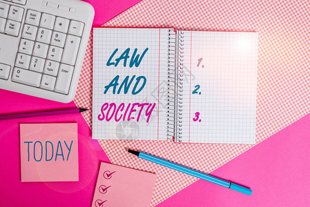 手写文字书写法律与社会概念照片解决法律与社会之间的相互关系书写设备和放置在彩色平桌上方图片