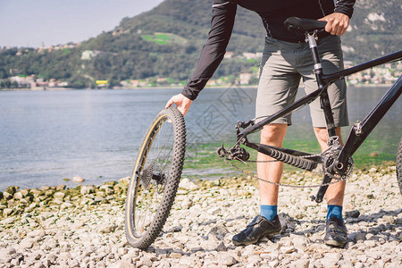 自行车修理修理山地自行车的人骑自行车的人在事故后轮案例中遇到麻烦人在意大利背景山湖附近修理自行车骑自行车的人在户外修图片