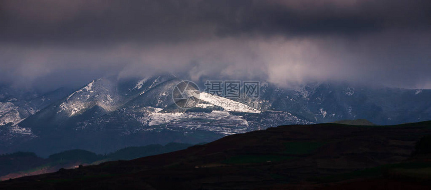 暴风雨笼罩在雪山的黑暗光芒中图片