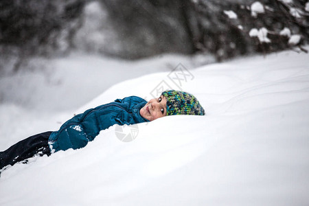 男孩躺在雪地里孩子穿过冬天的森林寒假孩子做图片